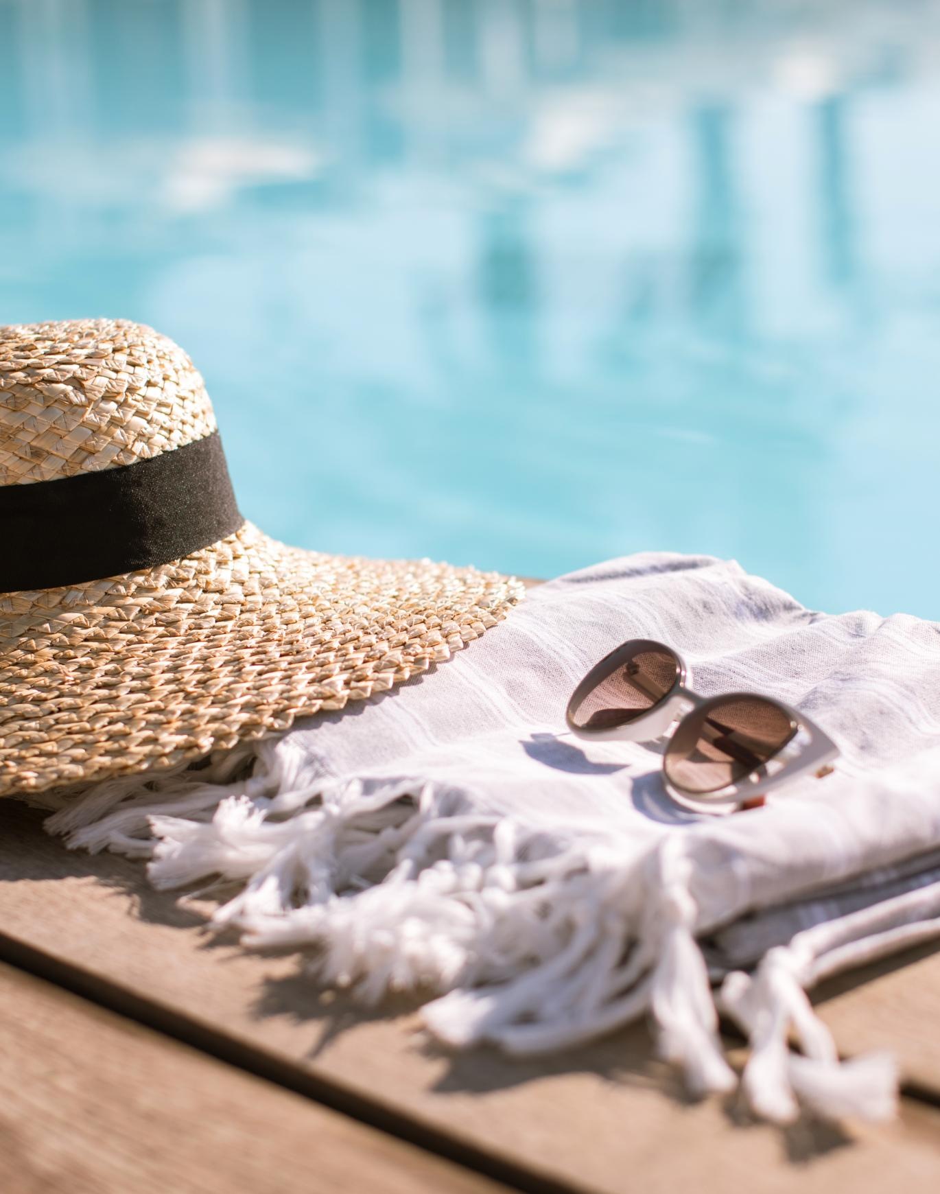 a hat and sunglasses by a pool