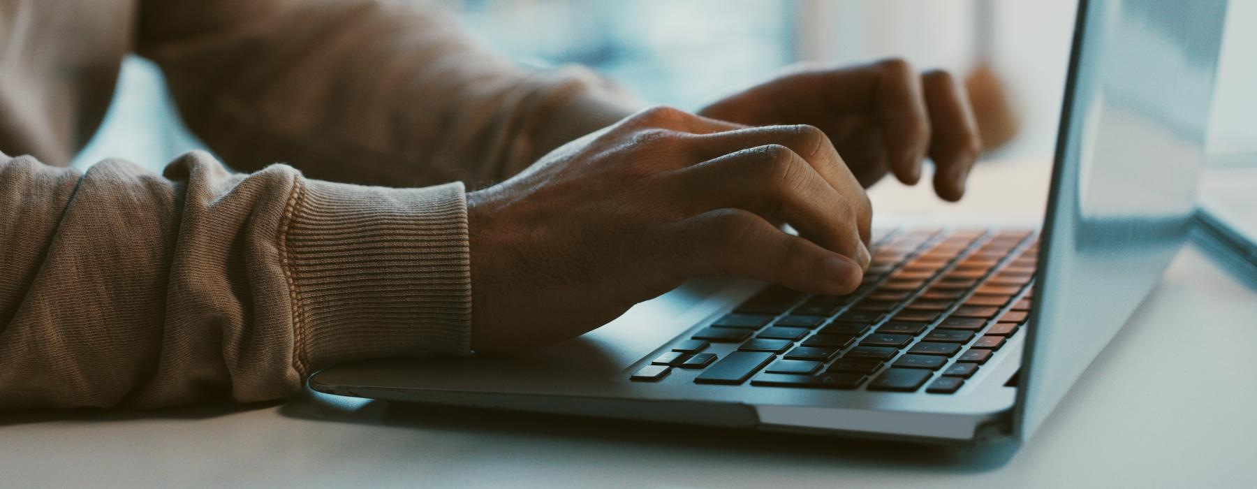 a close-up of hands typing on a laptop