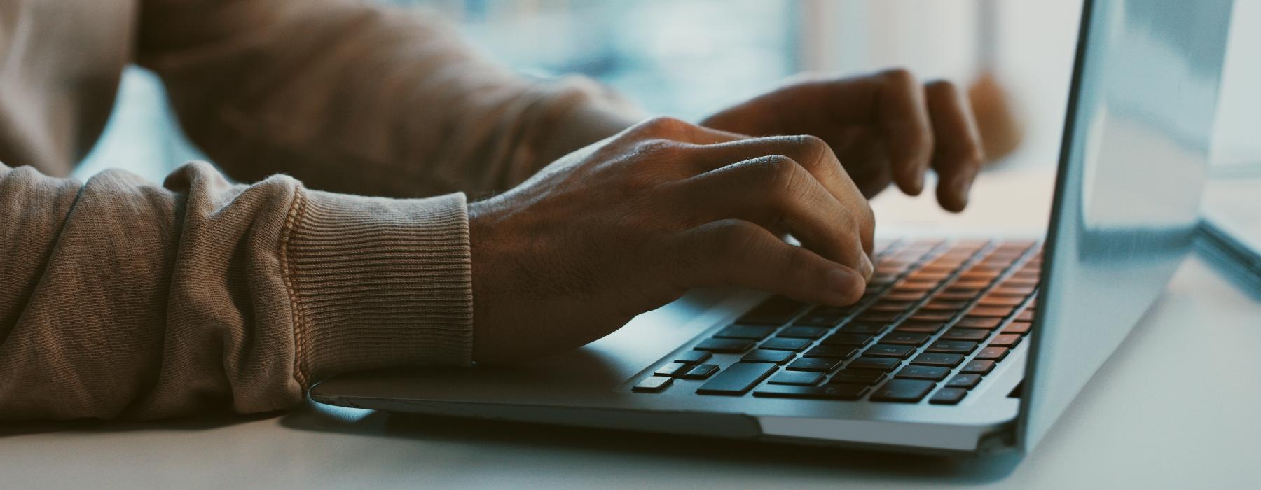 a close-up of hands typing on a laptop